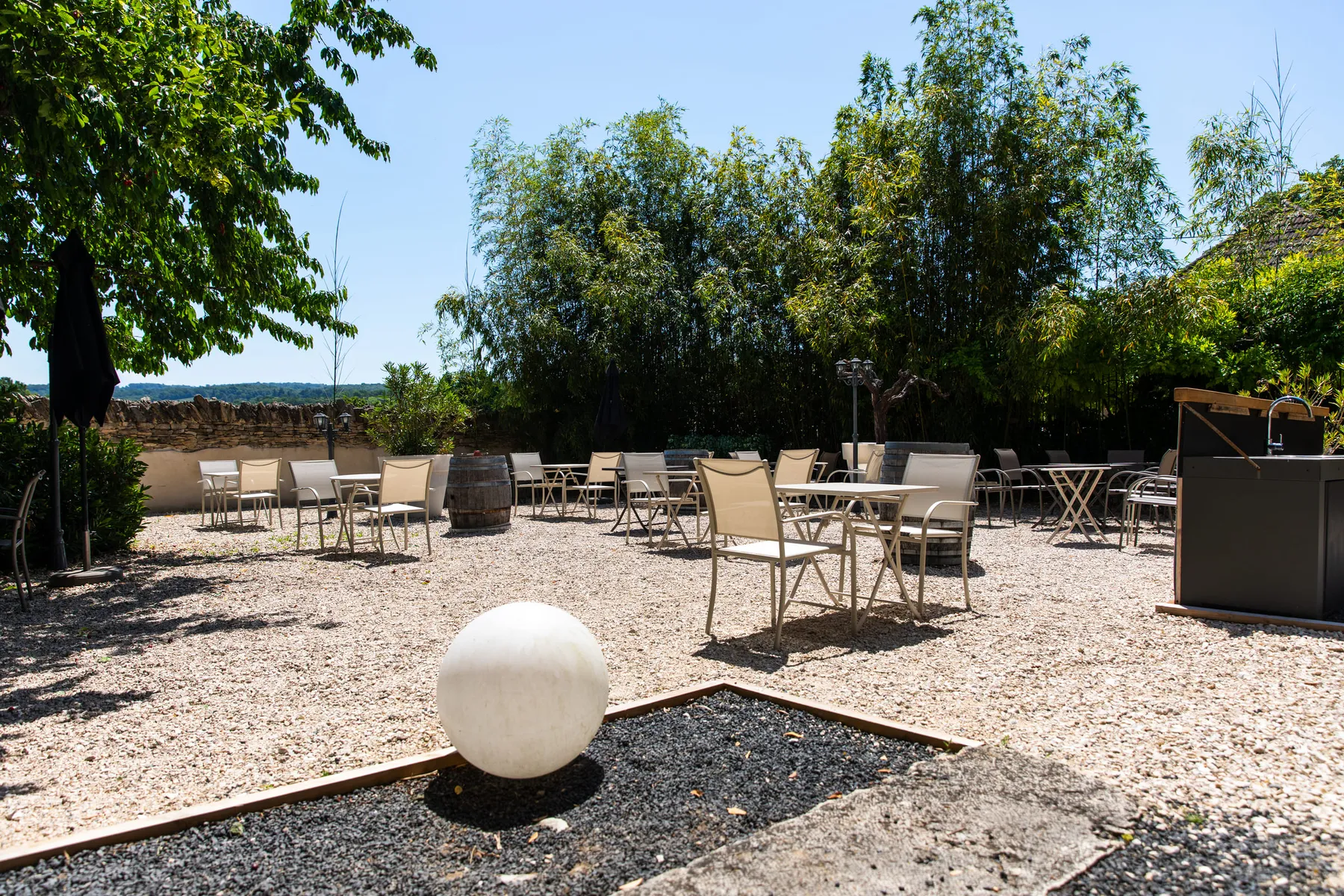 Tables et fauteuils installés sur la terrasse en gravier