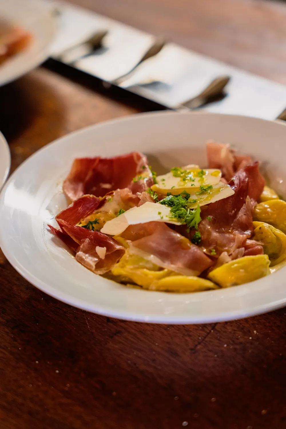 Assiette de ravioles gratinées, jambon cru et copeaux de parmesan
